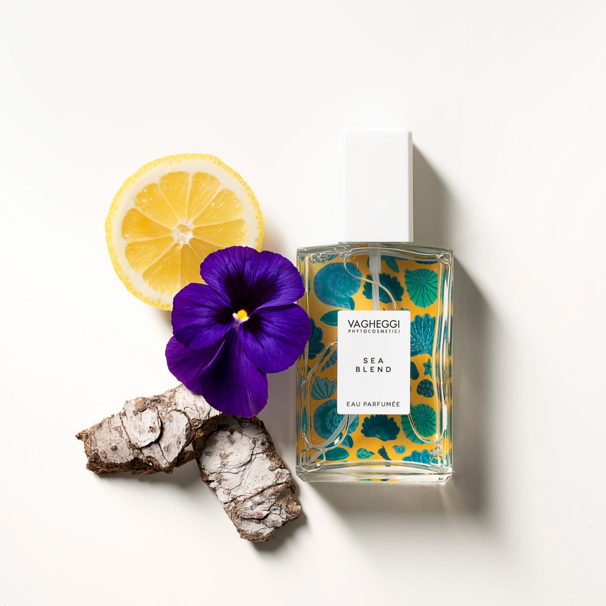 Vagheggi Fragrance Sea Blend, flacone con stampa turchese affiancato a agrumi e fiore viola