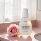 Urang True Rose Repair Essence, flacone in ambientazione con rose