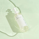 Anua Heartleaf Pore Control Cleansing Oil, flacone su sfondo verde acqua